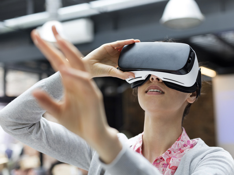 Woman with her arm stretched out reaching for something while wearing a VR headset